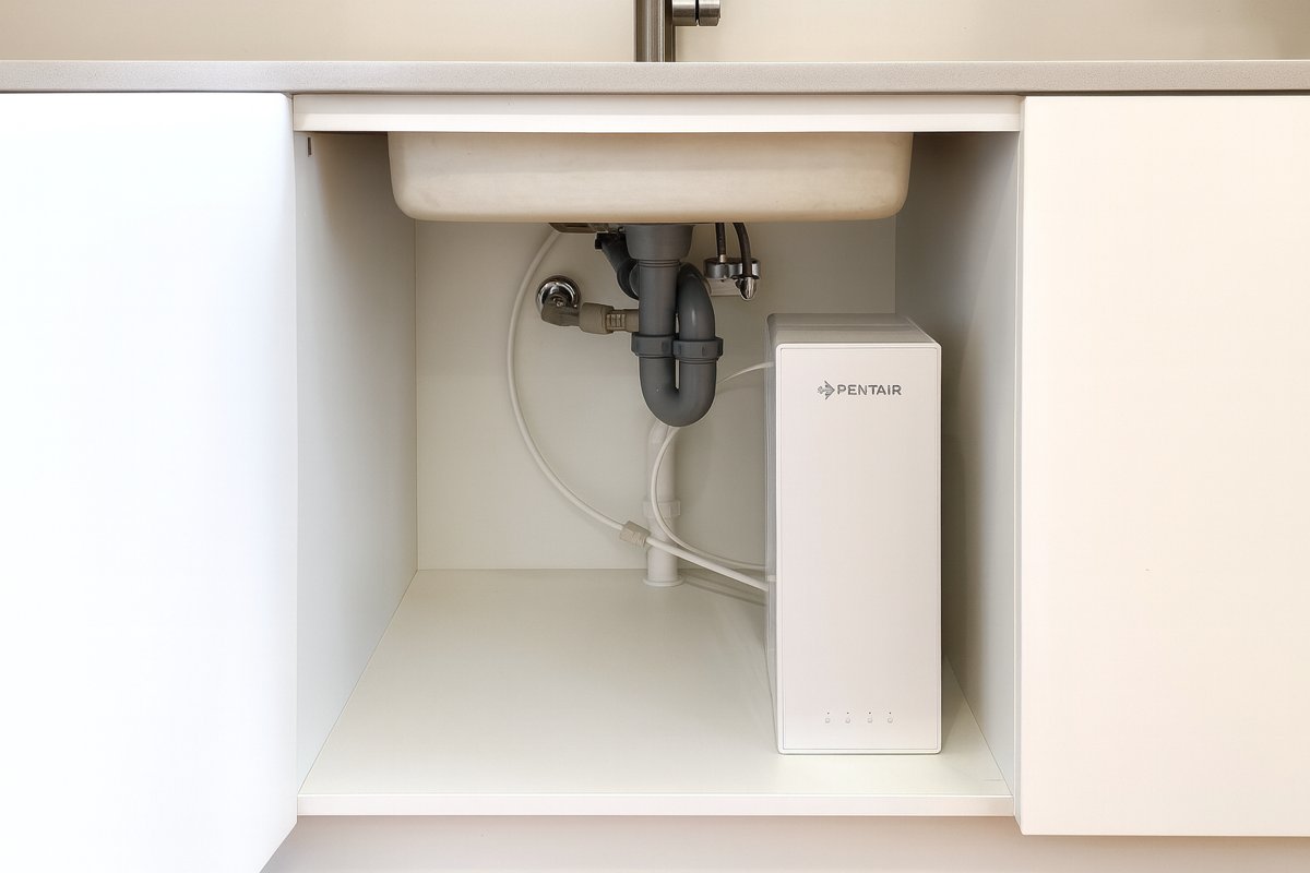 ES60 fitted under the sink in a minimal handleless white kitchen